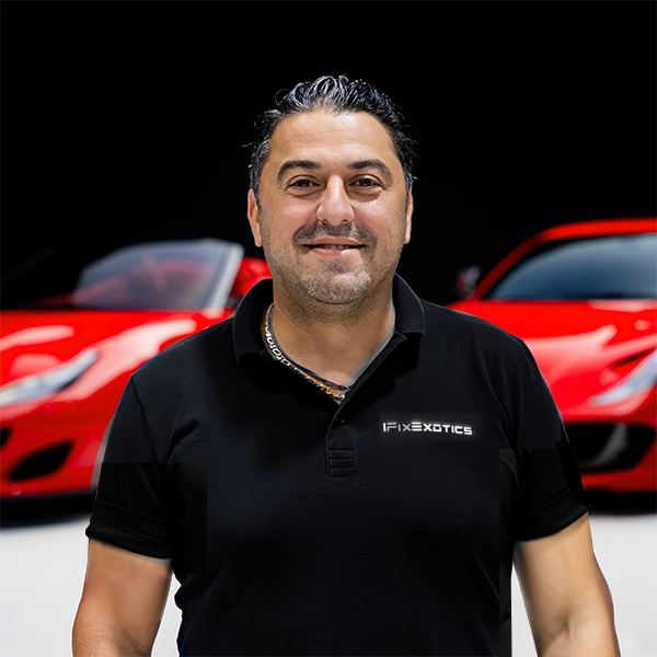 101png | Txtcharlie Man wearing a black polo with a 'Fix Exotics' logo, standing in front of red sports cars; he’s smiling at the camera.