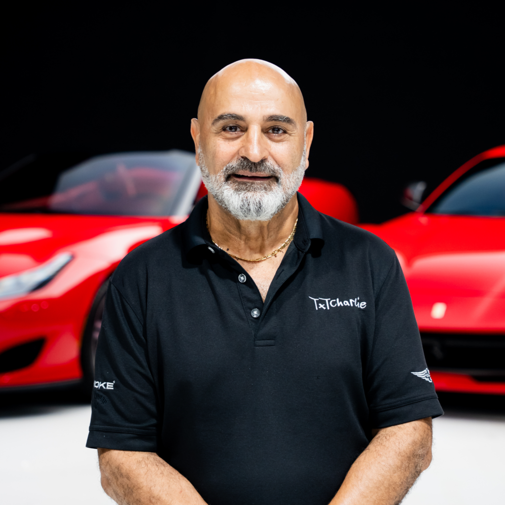252png | Txtcharlie Man with a shaved head and gray beard wearing a black polo, standing in front of a red car.