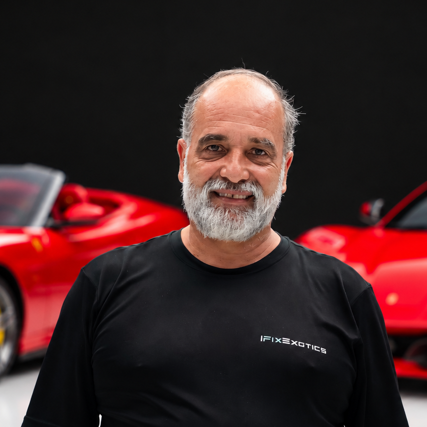 Yamirpng | Txtcharlie Smiling older man with a gray beard wearing a black IFIXEXOTICS shirt, standing in front of red sports cars.